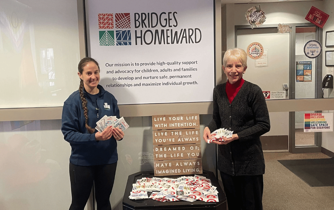Local nonprofit leader holds up a bunch of gift cards donated by the Building Impact network to help make the holidays brighter for those in need.