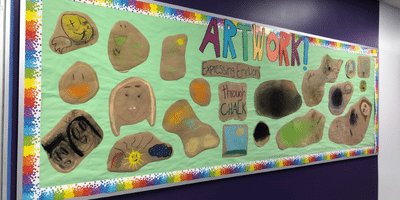 A wall of artwork made by youth attending a local nonprofit's program. This artwork was made using supplies from Building Impact Art Therapy Kits.
