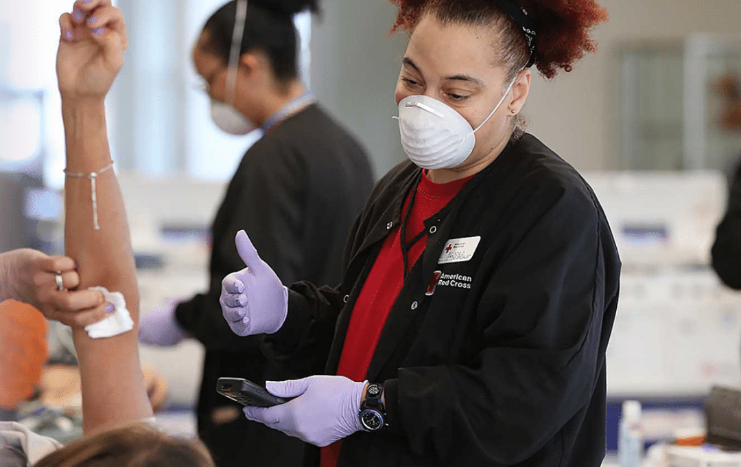 Red Cross nurse talks with a person donating blood.