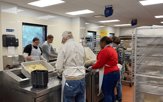 Volunteers packing meals at a nonprofit that supports community members with critical or chronic illnesses.