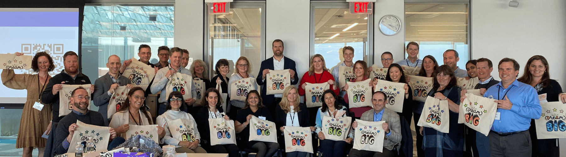 Volunteers holding up tote bags they customized as a part of an at-office volunteering project.