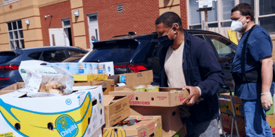 Volunteers moving boxes of produce during a food drive.